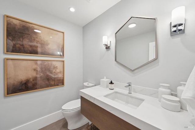 bathroom with baseboards, toilet, recessed lighting, wood finished floors, and vanity