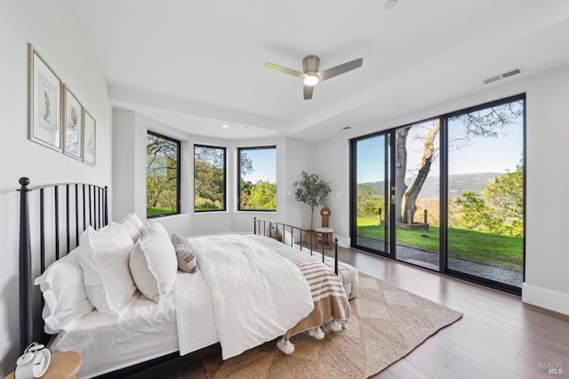 bedroom featuring access to outside, multiple windows, wood finished floors, and visible vents