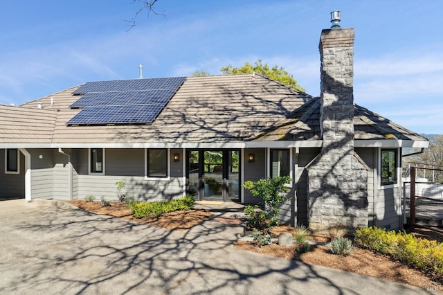 rear view of house featuring solar panels and a chimney