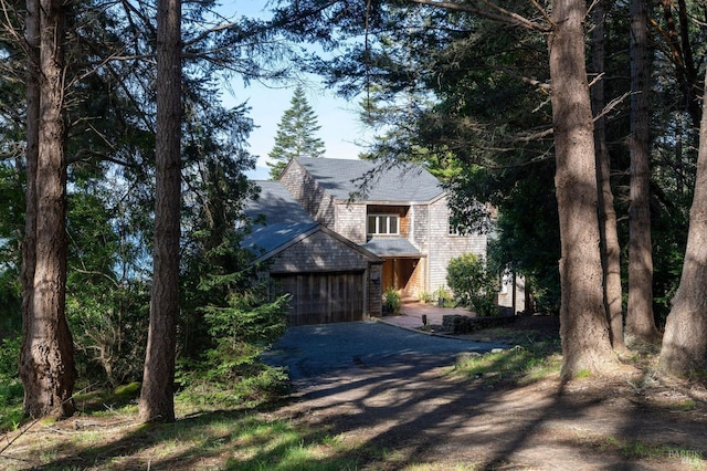 view of front facade featuring driveway, a garage, and roof with shingles