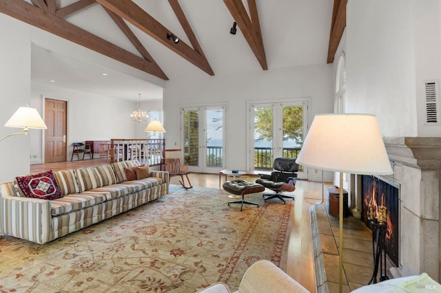 living room with a chandelier, a lit fireplace, beam ceiling, wood finished floors, and high vaulted ceiling