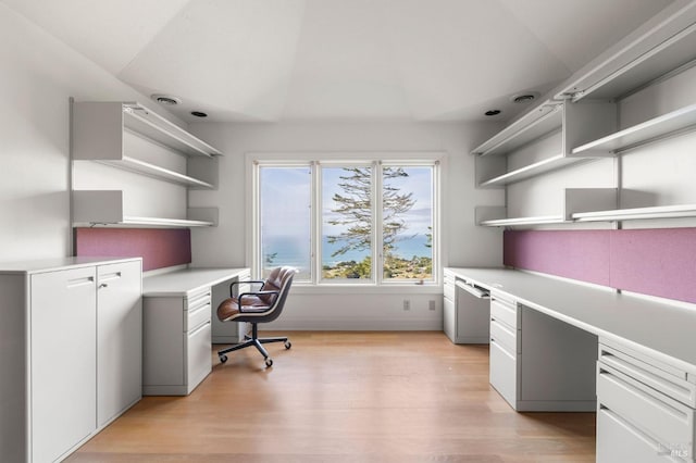 home office featuring light wood-style floors and built in desk