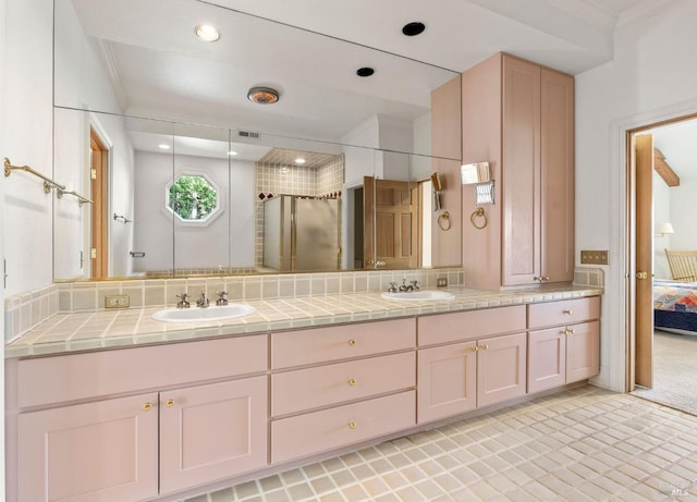 ensuite bathroom featuring a sink, decorative backsplash, and double vanity