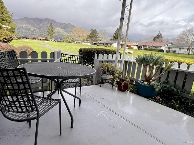 view of patio featuring a mountain view, outdoor dining space, and fence