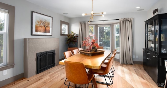 dining area featuring baseboards, recessed lighting, a fireplace, light wood-type flooring, and a chandelier