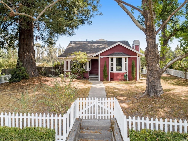 bungalow-style home featuring a porch, a fenced front yard, and a chimney