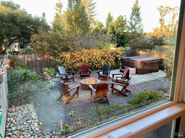view of patio featuring an outdoor fire pit, a hot tub, and fence