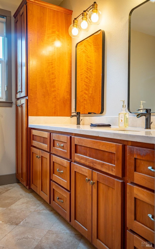 bathroom with double vanity, baseboards, and a sink