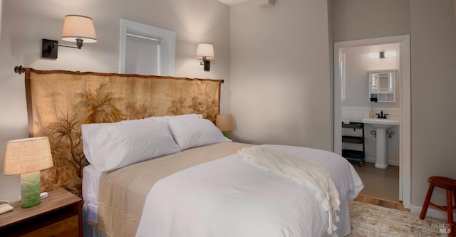 bedroom featuring ensuite bath, wood finished floors, and a sink