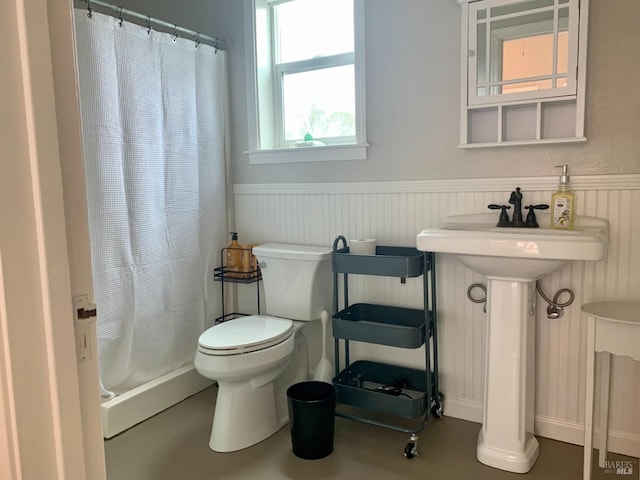 bathroom featuring a wainscoted wall, curtained shower, and toilet