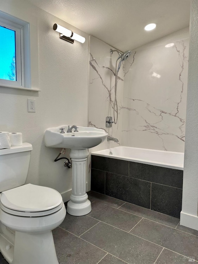 bathroom with a textured ceiling, toilet, tiled shower / bath, and a textured wall