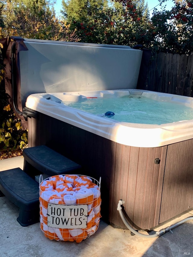 view of patio with a hot tub and fence