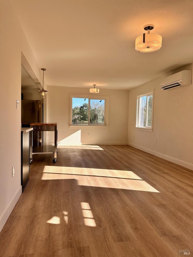 unfurnished room with a wall mounted AC, baseboards, and dark wood-style flooring