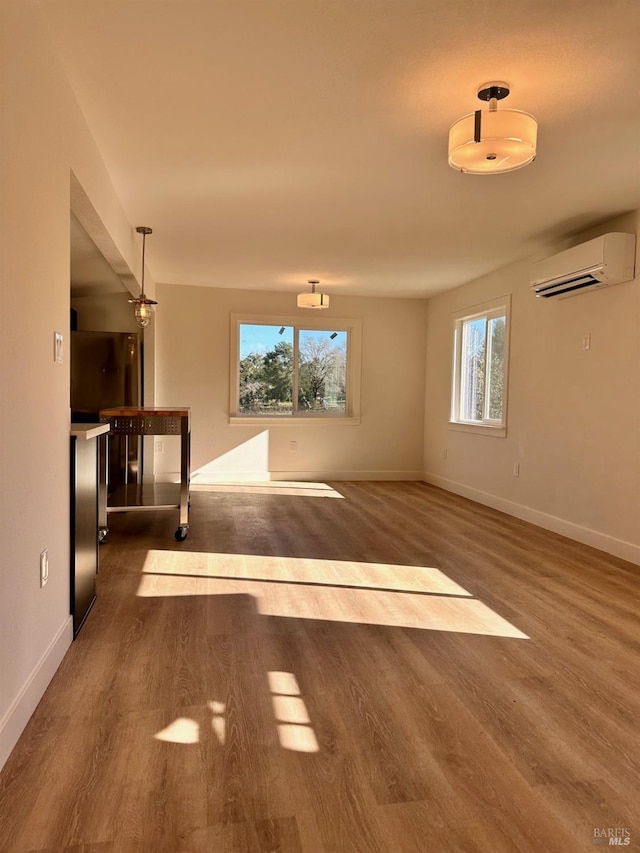 interior space with a wall mounted air conditioner, baseboards, and dark wood-type flooring