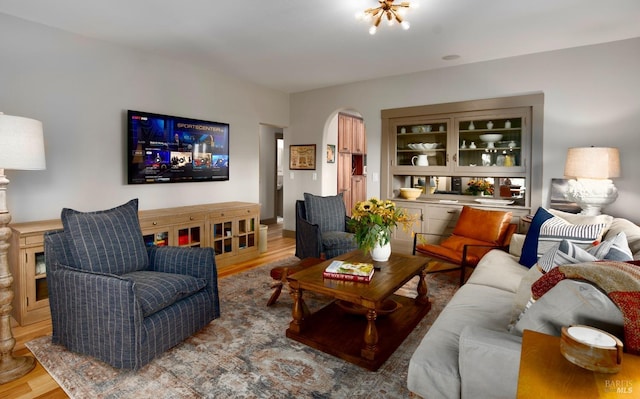 living area with arched walkways and wood finished floors