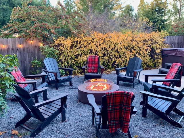 view of patio / terrace with fence, a hot tub, and an outdoor fire pit