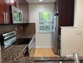 kitchen featuring dark brown cabinets, stainless steel appliances, baseboards, and wood finished floors