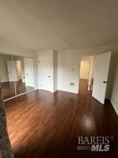 unfurnished room featuring a textured ceiling and dark wood-style floors