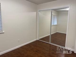 unfurnished bedroom featuring a closet, baseboards, and wood finished floors