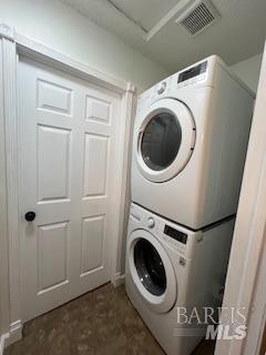 laundry area with laundry area, stacked washer and dryer, and visible vents