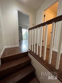 stairs featuring wood finished floors and baseboards