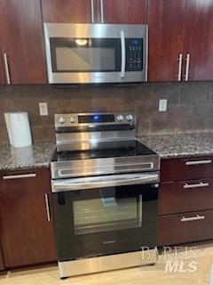 kitchen with decorative backsplash, dark stone countertops, and appliances with stainless steel finishes