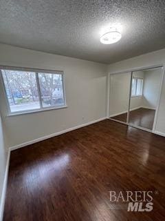 unfurnished bedroom featuring multiple windows, a textured ceiling, and wood finished floors