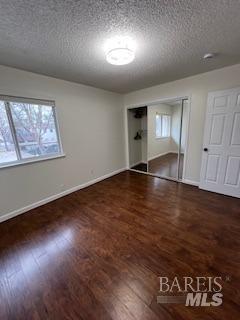 unfurnished bedroom with wood finished floors, baseboards, and a textured ceiling