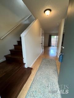 hallway featuring stairway, a textured ceiling, and wood finished floors
