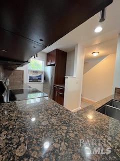 kitchen with dark stone counters and freestanding refrigerator