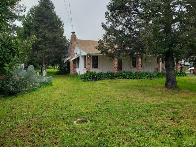 view of home's exterior with a yard, brick siding, and a chimney