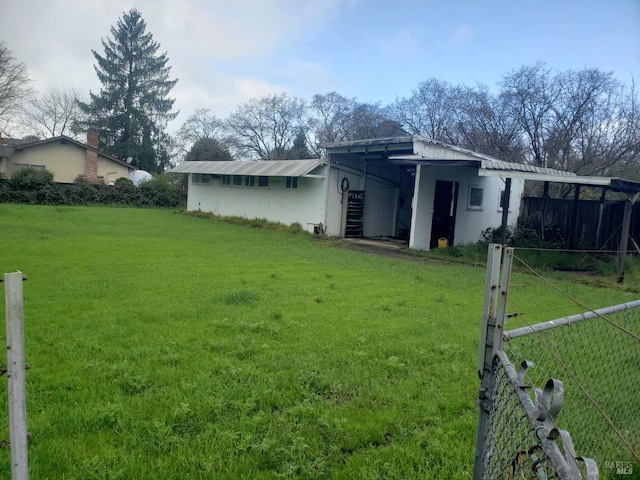 back of house with fence, a pole building, a yard, an outdoor structure, and a carport