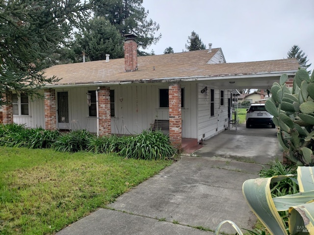 view of front facade featuring an attached carport, board and batten siding, concrete driveway, a front yard, and roof with shingles