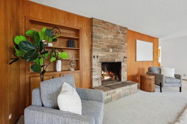 living area with a stone fireplace, wooden walls, carpet, and a textured ceiling