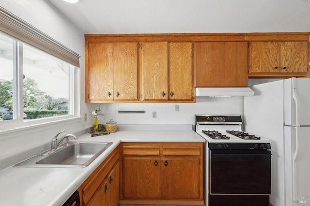 kitchen featuring a sink, light countertops, under cabinet range hood, brown cabinetry, and gas range oven