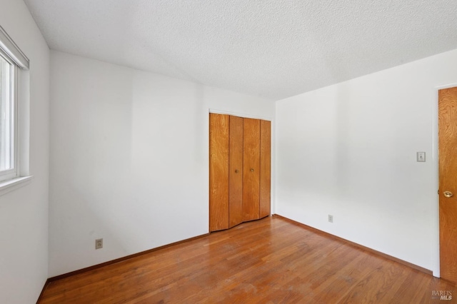 unfurnished room featuring a textured ceiling, baseboards, and wood finished floors