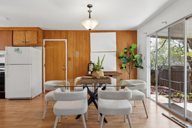 dining space featuring wood walls and light wood-style floors