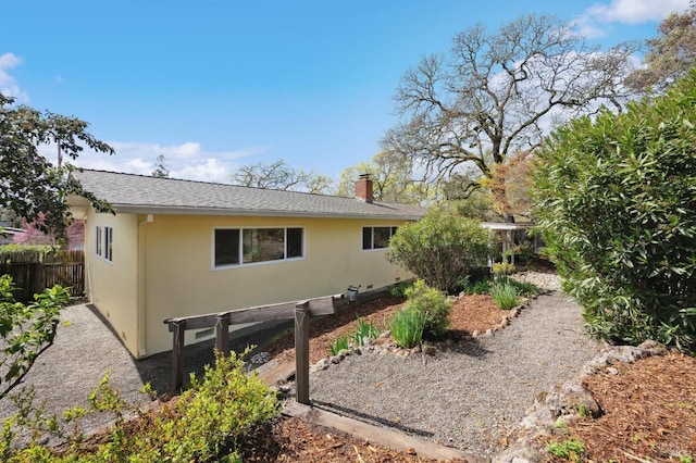 view of property exterior with fence, a chimney, roof with shingles, and stucco siding