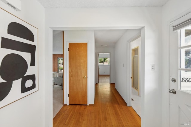 corridor with plenty of natural light, visible vents, and light wood-type flooring