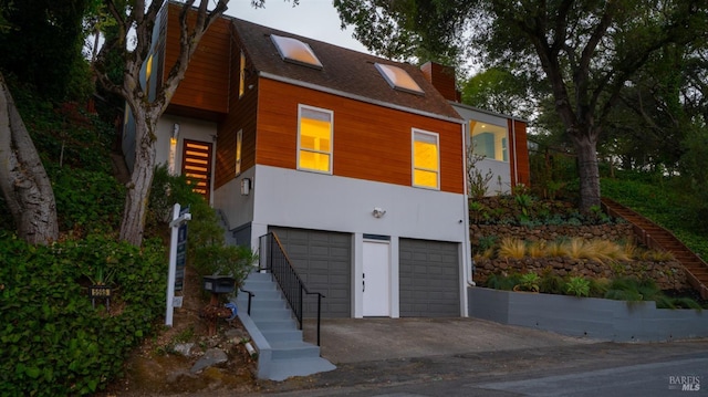 view of front of house featuring a garage, stairway, concrete driveway, and roof with shingles