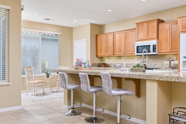 503 Twin Lakes Ln, Rio Vista, CA 94571 - kitchen with baseboards, white microwave, recessed lighting, a breakfast bar, and light tile patterned floors