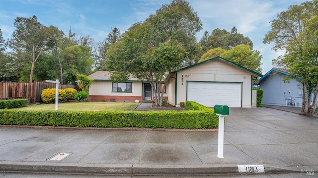 ranch-style house featuring an attached garage, driveway, a front yard, and fence