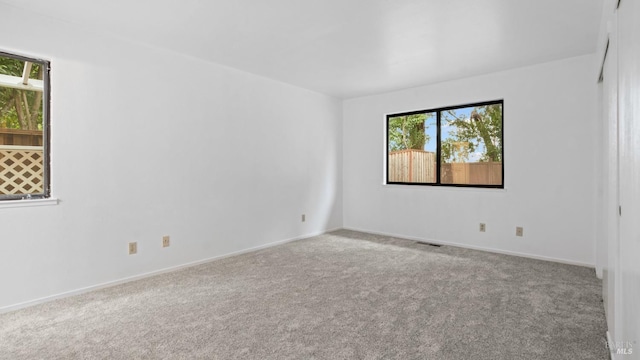 carpeted empty room featuring visible vents and baseboards