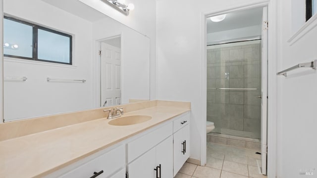 full bath with tiled shower, toilet, vanity, and tile patterned flooring