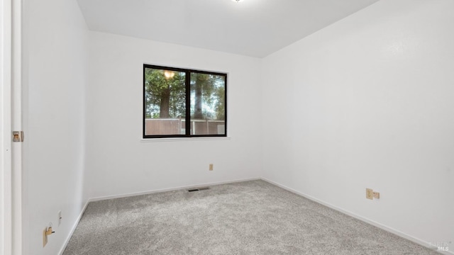 carpeted spare room with visible vents and baseboards