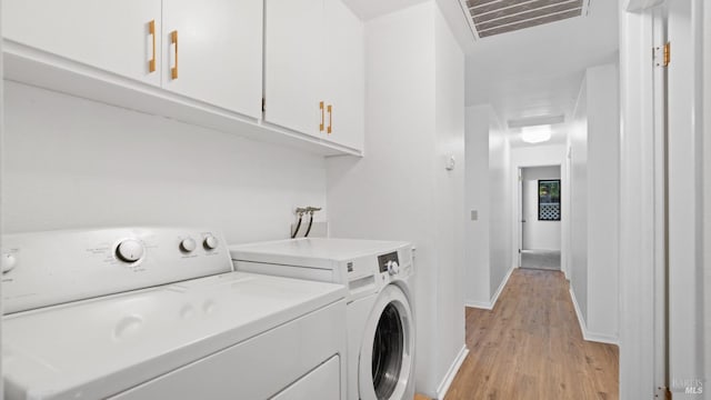 laundry room with visible vents, baseboards, light wood finished floors, and washing machine and clothes dryer