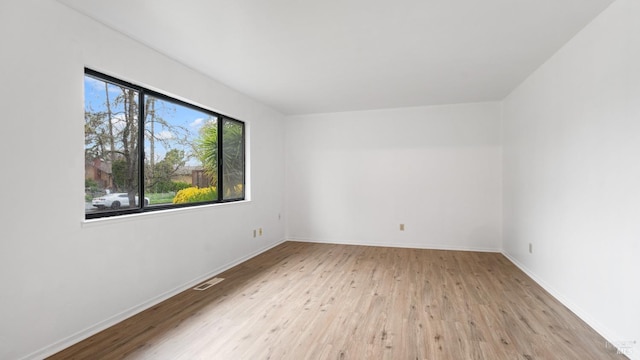 unfurnished room with wood finished floors, visible vents, and baseboards