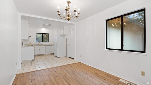 unfurnished dining area with visible vents, baseboards, a notable chandelier, and light wood finished floors