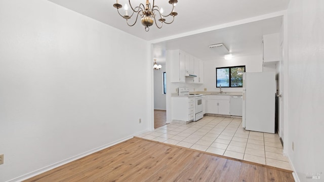 kitchen with a sink, white appliances, an inviting chandelier, white cabinets, and light countertops