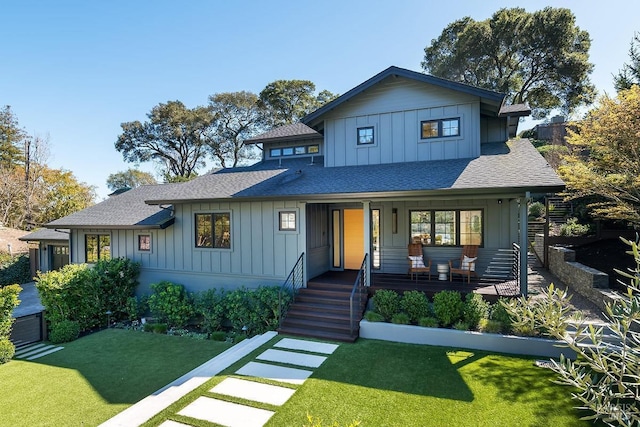 view of front facade featuring a front yard, a porch, board and batten siding, and roof with shingles
